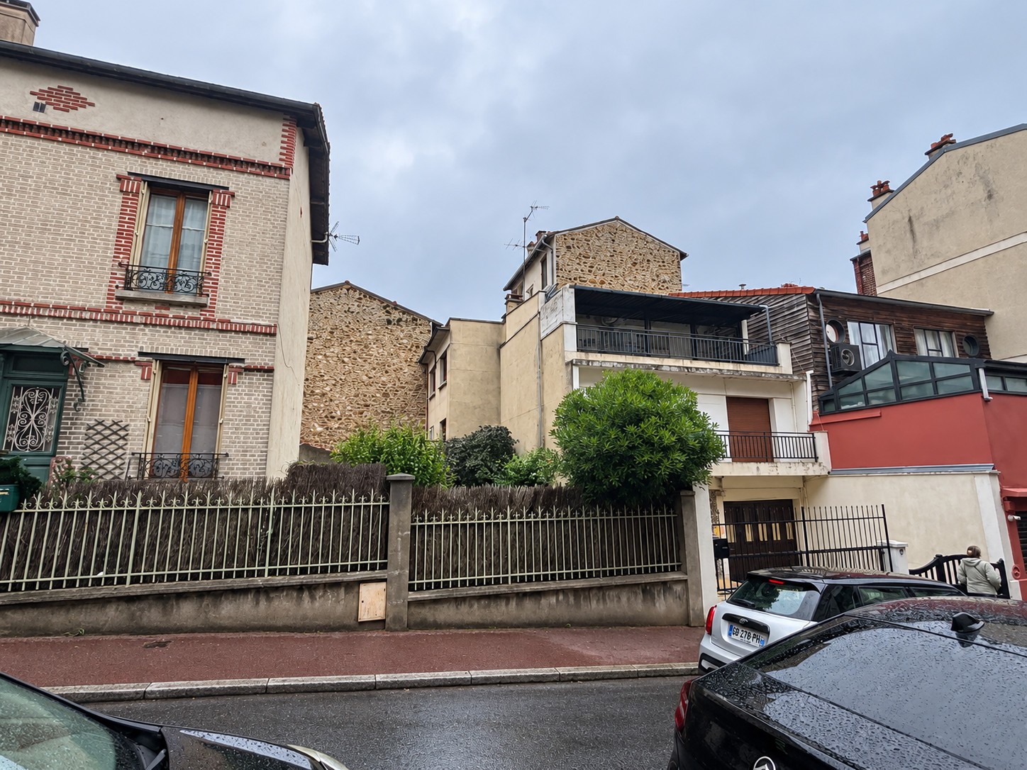 Façade existante de la maison à Suresnes vue depuis la rue, avec balcons, toiture légère et portail métallique.