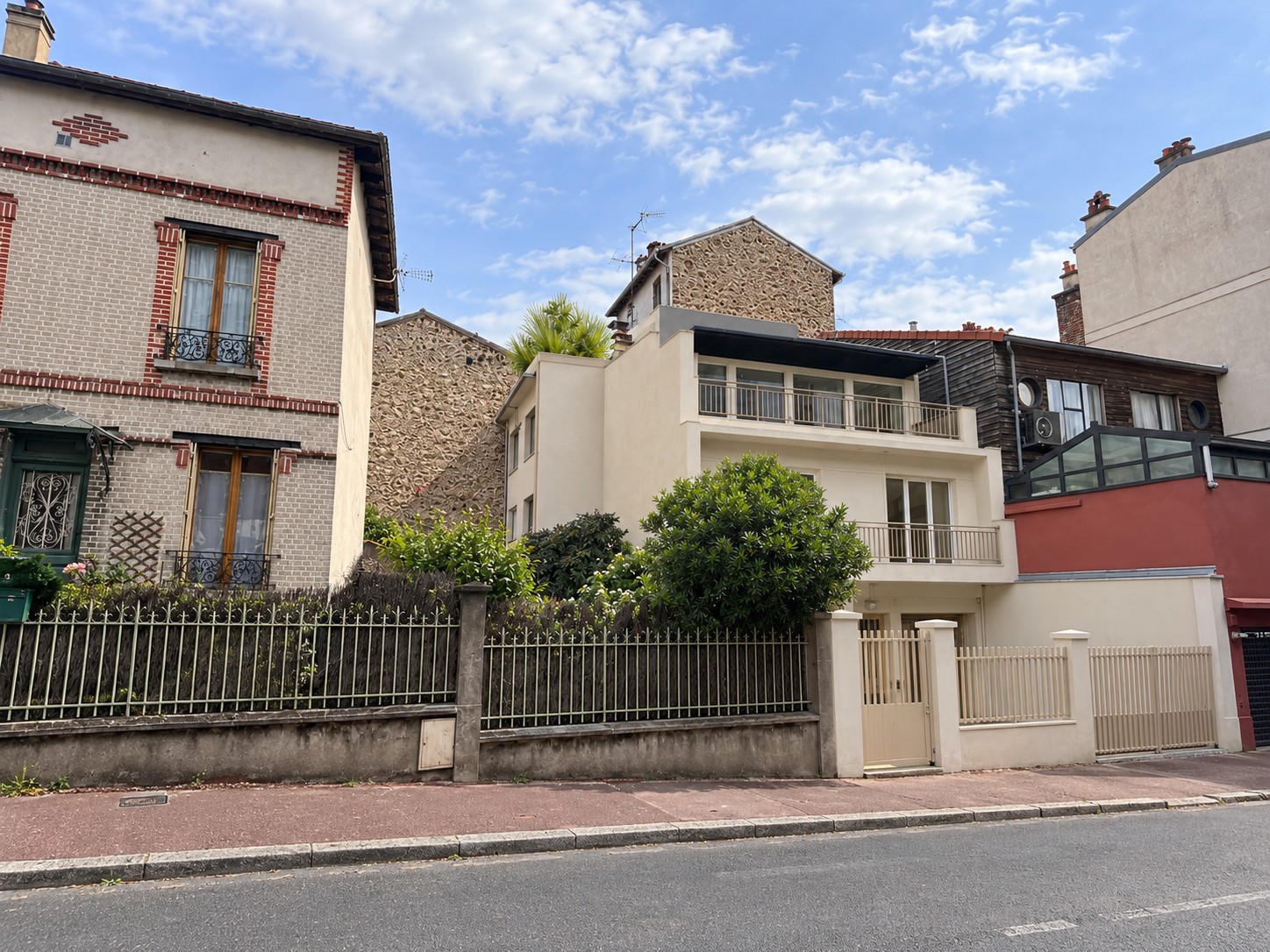 Vue du projet à Suresnes depuis la rue, avec façade claire, balcons, terrasse plantée et clôture sur rue.
