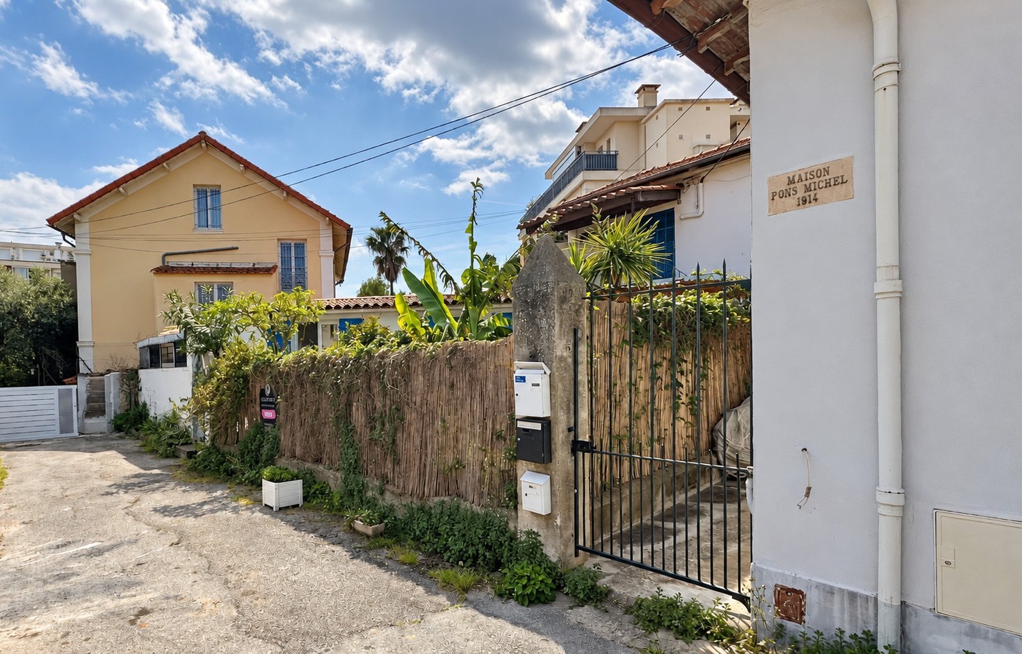 État existant de la maison à Cannes depuis la ruelle, avec volume bas, clôture végétalisée et portail métallique.