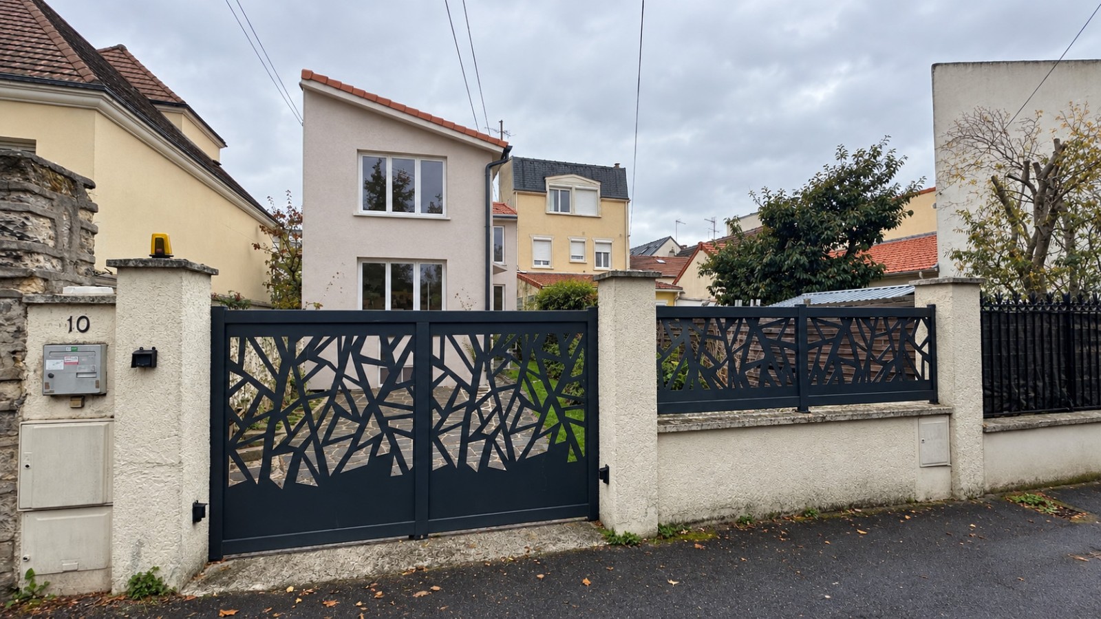 Projet de surélévation d’une maison à Colombes, avec enduit clair, toiture monopente et portail anthracite.