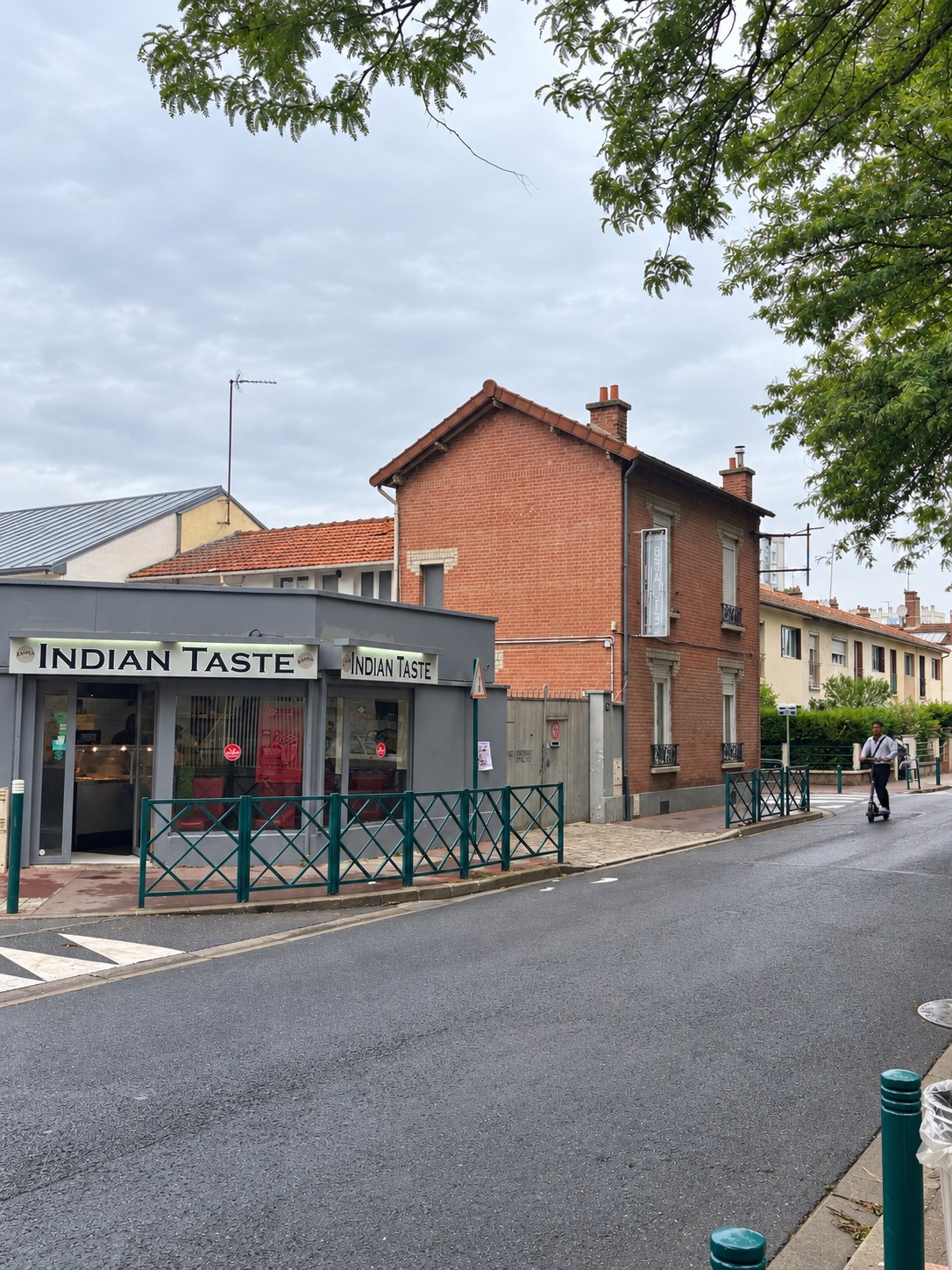 Bâtiment existant en brique à Gennevilliers, sous toiture en tuiles, à côté d’un commerce sur rue.